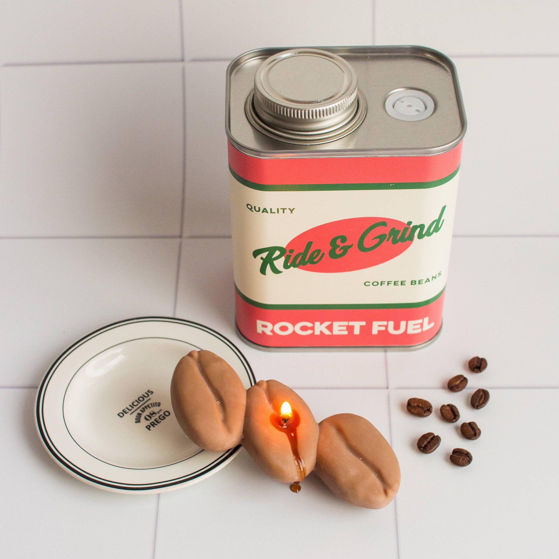 Can of 'Ride & Grind Rocket Fuel' coffee beans with coffee beans and a candle on a white surface.